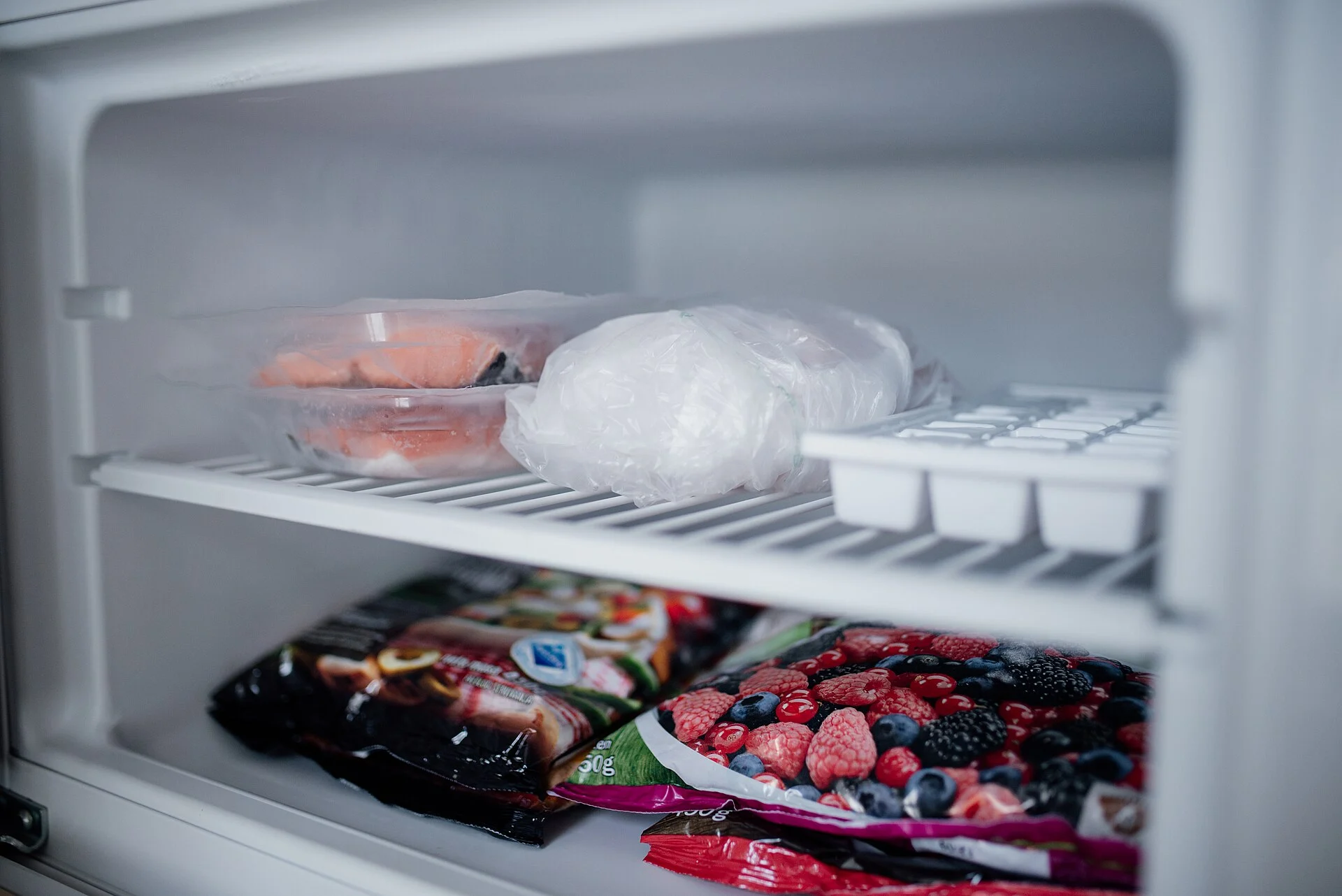Пакеты с замороженными продуктами и контейнеры в морозильной камере